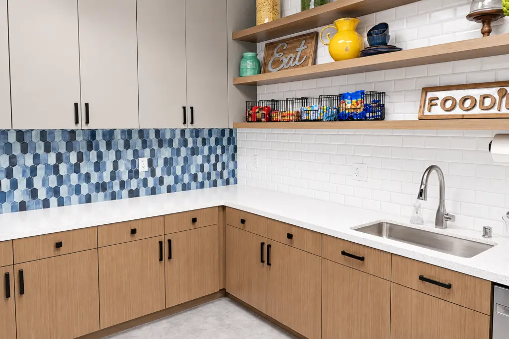 FWCSE employee break room kitchenette in Irvine with blue tile backsplash and open wood shelving