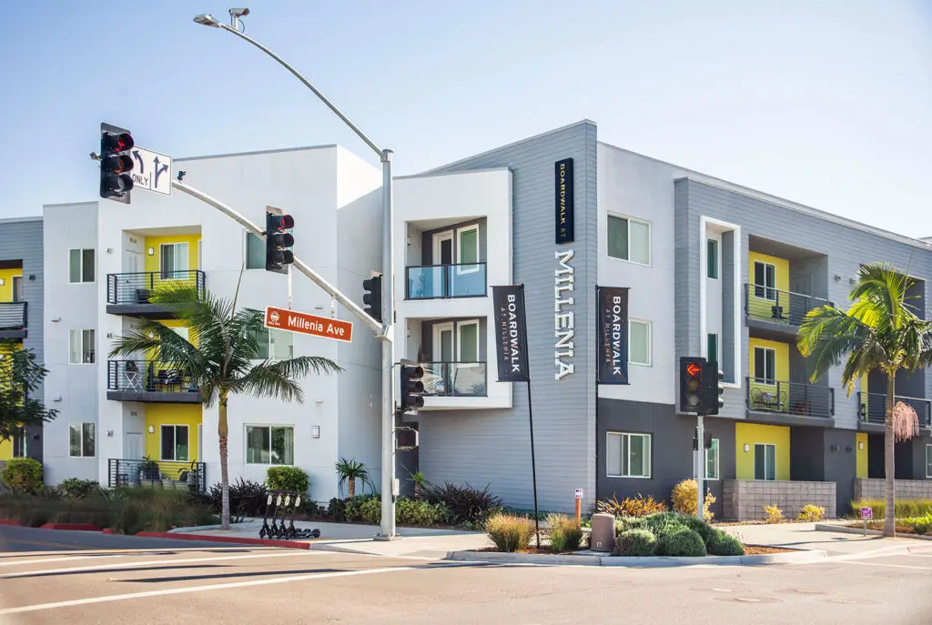 Boardwalk at Millenia apartments in Chula Vista, California, a four-story multifamily building with white, gray, and yellow facades at the corner of Millenia Avenue