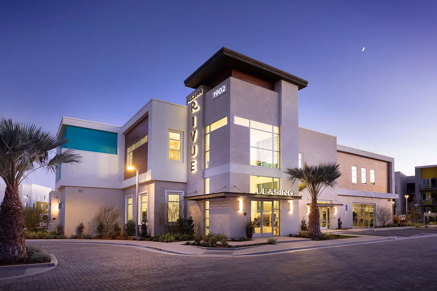 Alexan Rivue apartment community in Chula Vista with illuminated leasing center and contemporary architecture at dusk