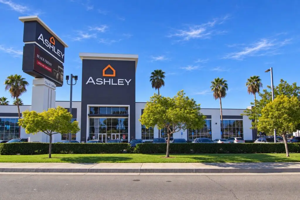 Front elevation of Ashley Furniture Colton with the entry tower, pylon sign, and landscaped street edge