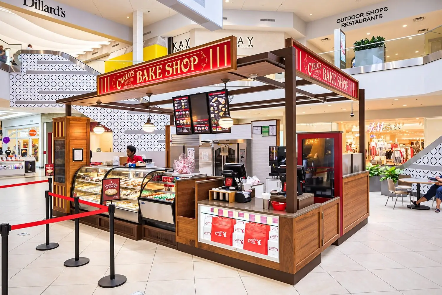 Carlo’s Bakery kiosk at Perimeter Mall with pastry displays, branded canopy, and customer queue