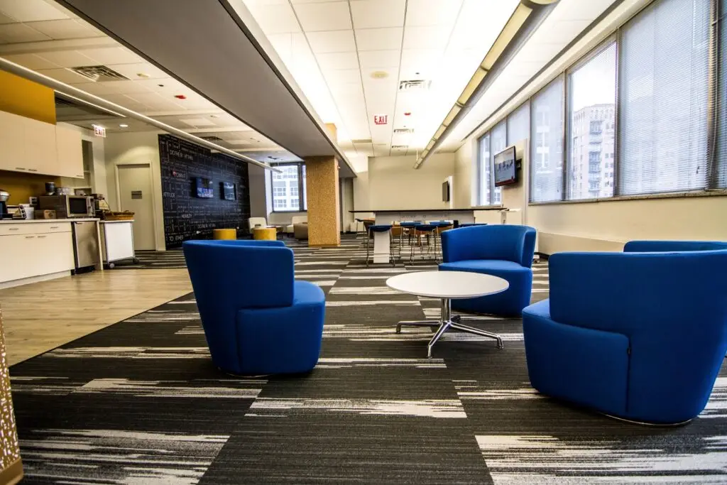 Lounge at the Chicago corporate office with blue swivel chairs, a round white table, and a window wall over the city
