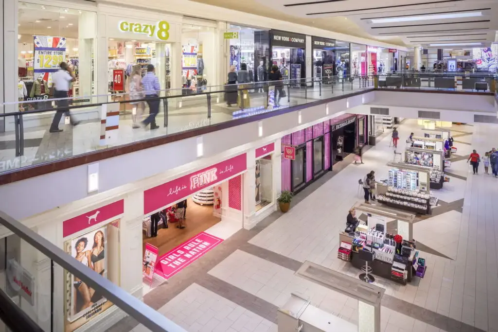 Upper concourse at Cumberland Mall in Atlanta, Georgia, with Crazy 8 on the second level, PINK on the ground floor, Victoria's Secret beyond, and kiosks along the tiled court.