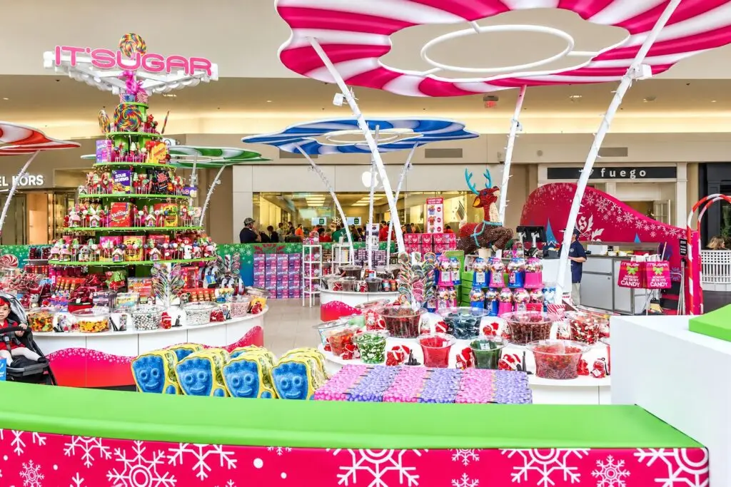 IT'SUGAR holiday candy kiosk at Baybrook Mall in Friendswood, Texas with colorful displays, oversized candy canopies, and seasonal graphics