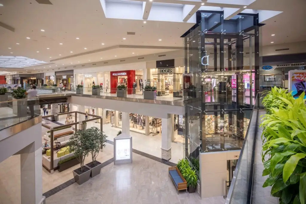 Two-level court at Perimeter Mall Atlanta with a glass elevator, seating, and renovated storefronts