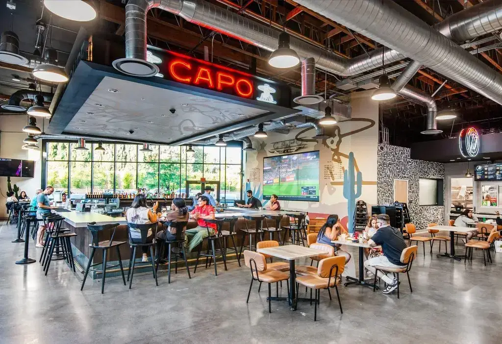 Rodeo 72 bar and dining area in Whittier, California, with exposed ductwork, wood structure, and communal seating