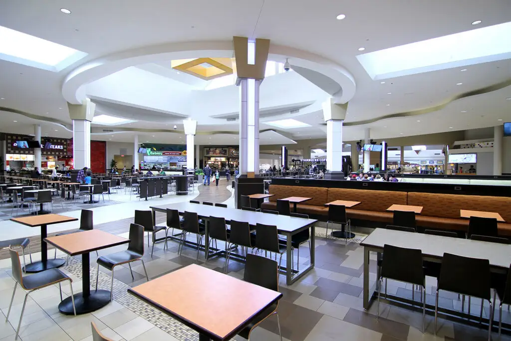 Food court at The Shops at Mission Viejo with curved white ceilings, skylights, banquettes, and tenant fronts including Rubio’s and Starbucks