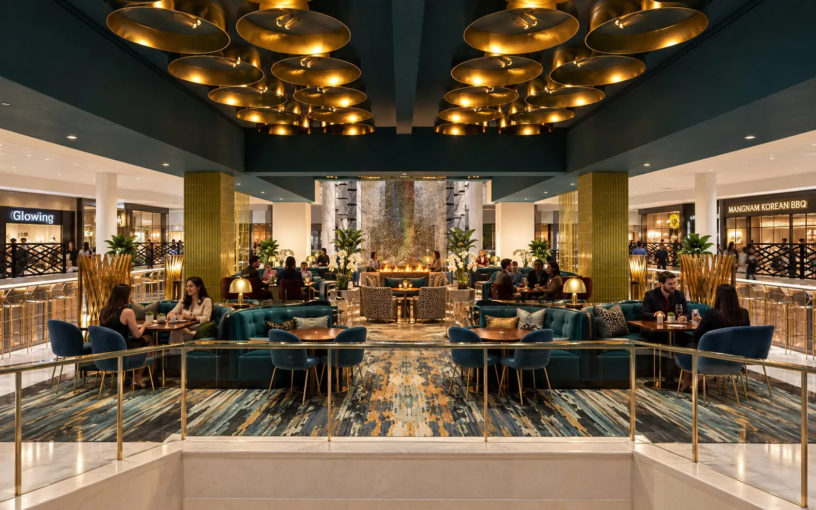 Dining lounge at Stonestown Galleria in San Francisco, seen from the stair with a gold rail, teal banquettes, gold disc pendants, and a water-wall fireplace, with Glowing and Mangnam Korean BBQ storefronts beyond.