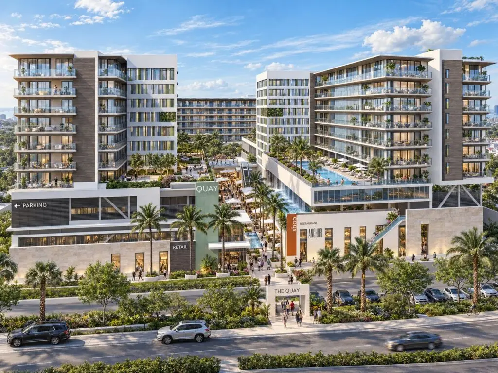 Conceptual rendering of The Quay, a mixed-use development featuring residential towers, elevated pool decks, retail, restaurants, and a central pedestrian promenade lined with palm trees.