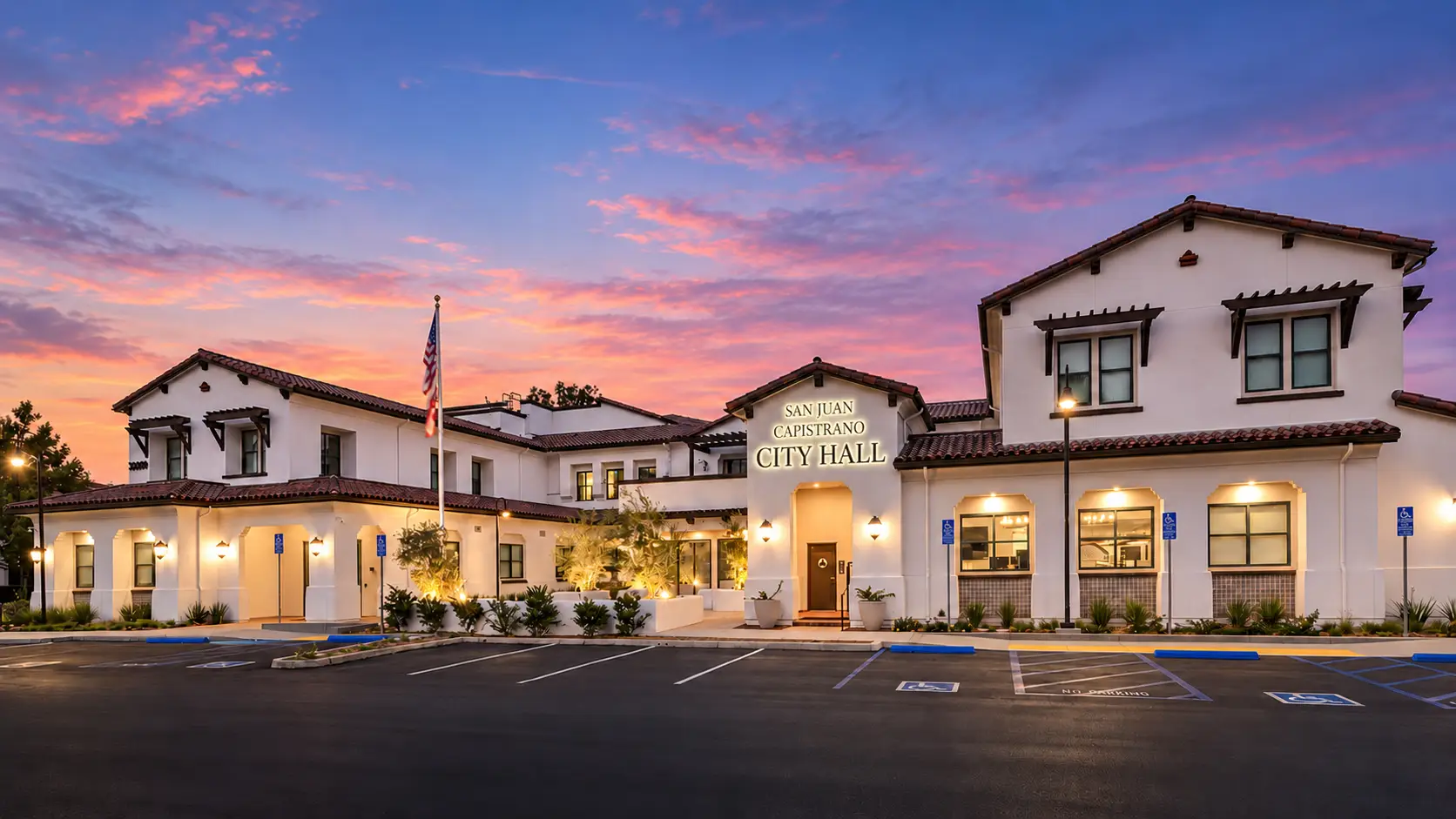 San Juan Capistrano City Hall at dusk with Spanish Colonial architecture and illuminated entry signage